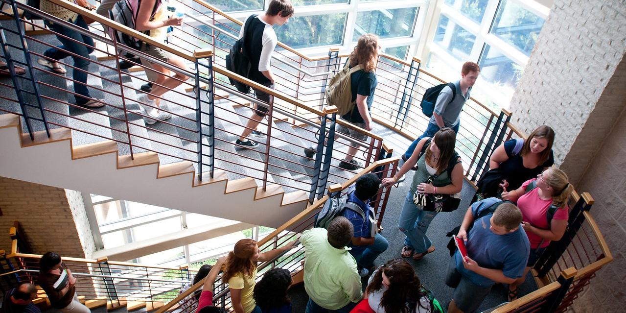 Students descending a staircase with glass windows